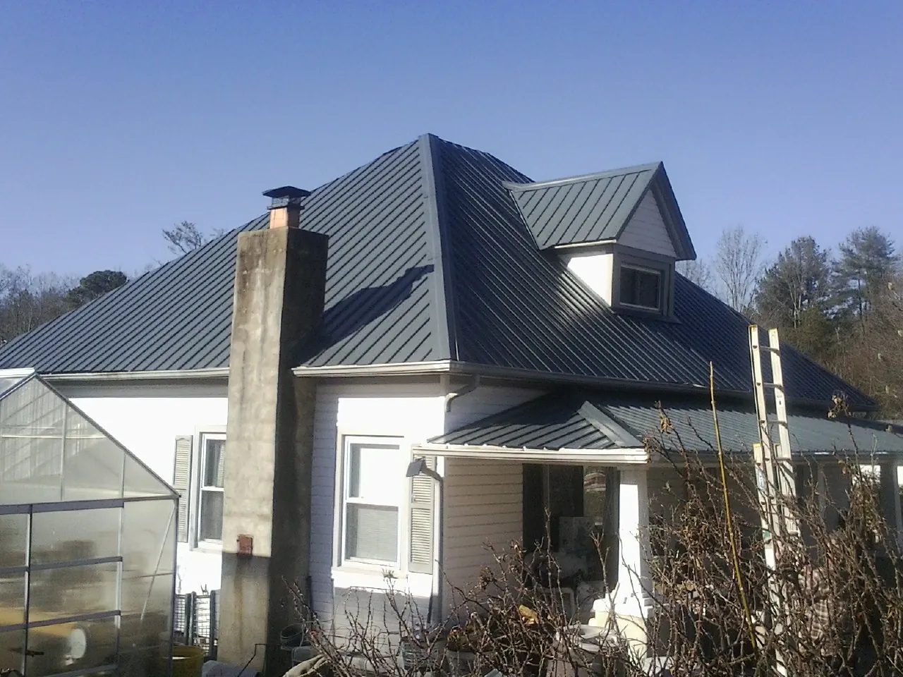 Dark blue standing seam metal roof on a white farmhouse with dormer — Slate & Tile Roof Repair by Roofing Brothers in Lonaconing
