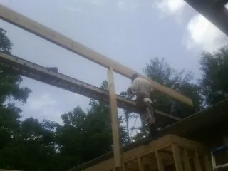 Carpenter setting a ridge beam over a new addition frame — Ice Dam Removal by Roofing Brothers in Lonaconing