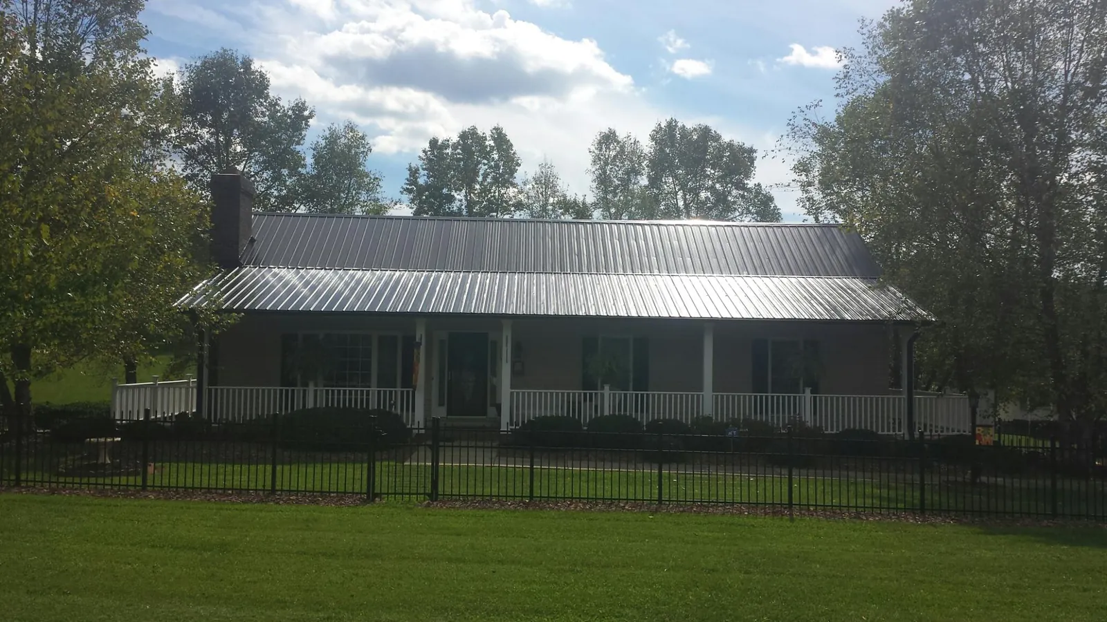 Gray metal roof on a brick ranch with a full width front porch — Gutter Guard Installation work by our crew in Lonaconing