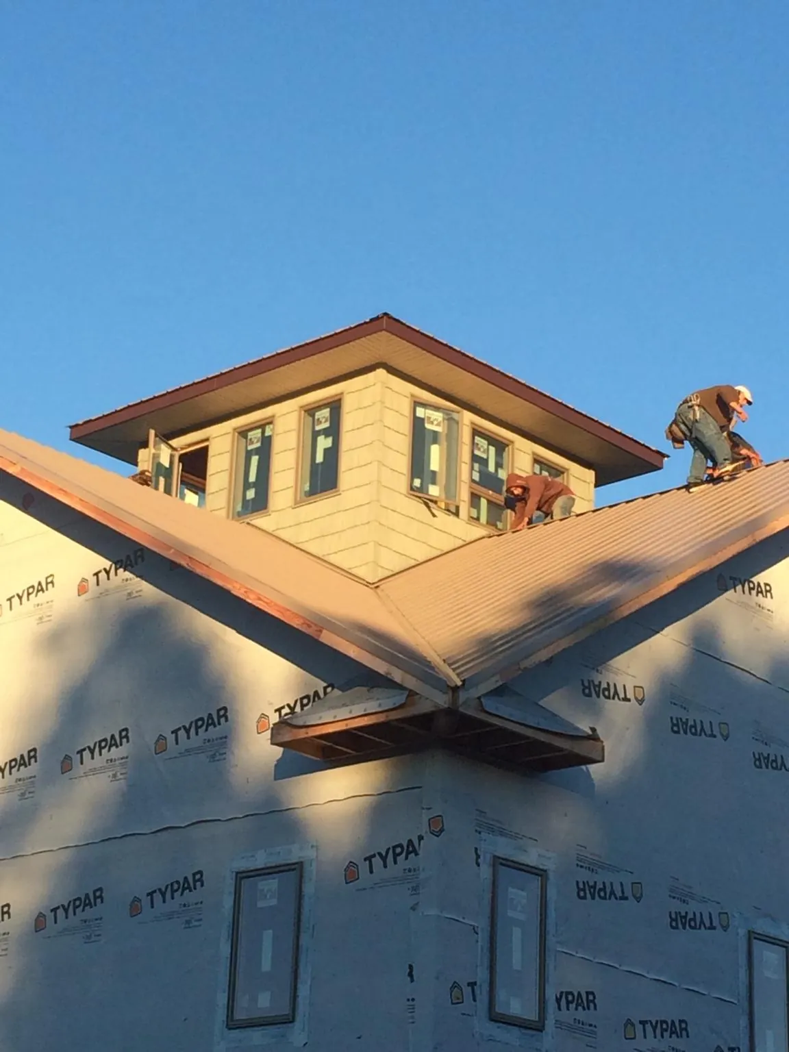 Roofers working around a rooftop cupola on a new metal roof at sunset — Roof Waterproofing in Lonaconing by Roofing Brothers